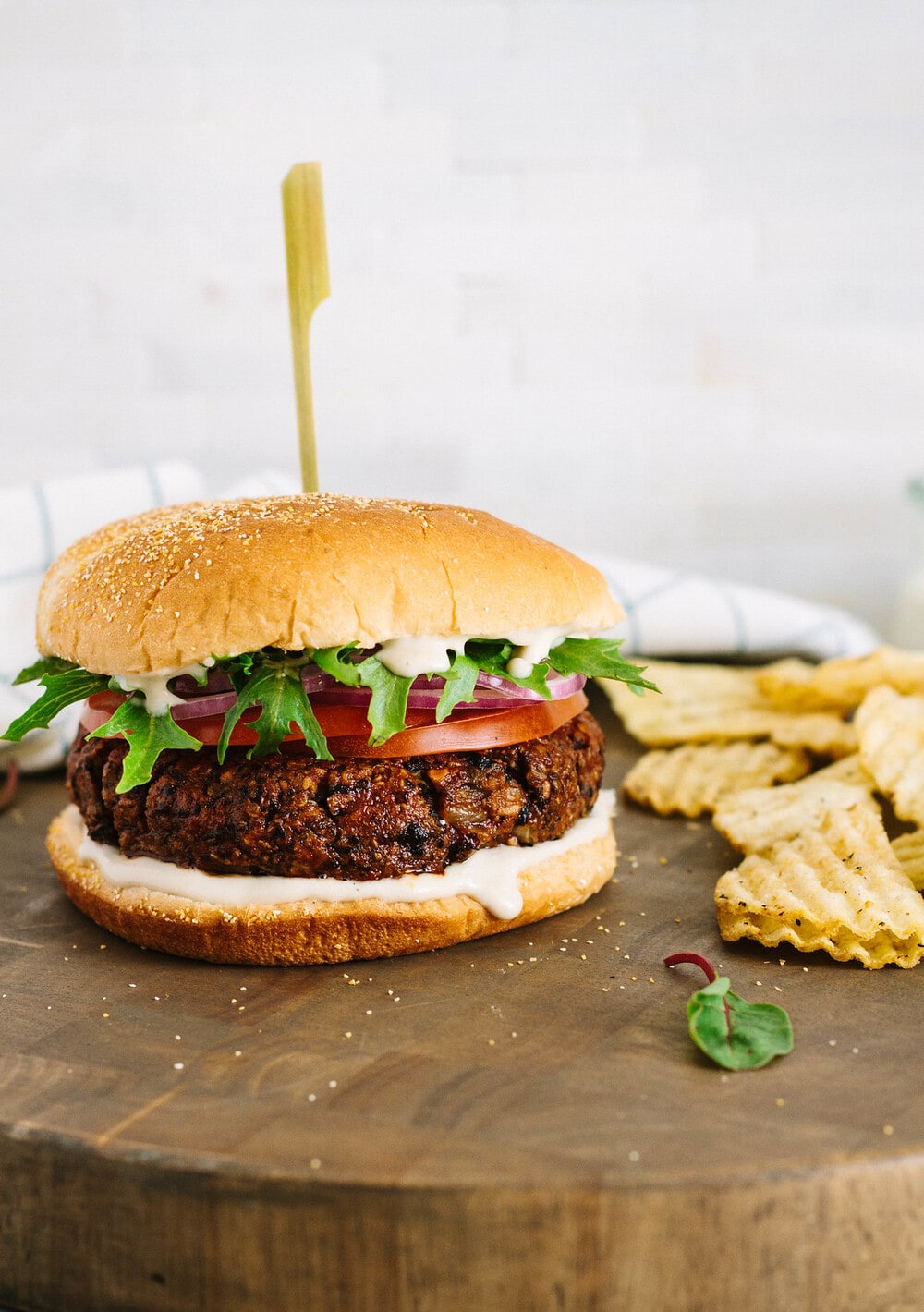 healthy black bean burger fully loaded on a wooden serving board.