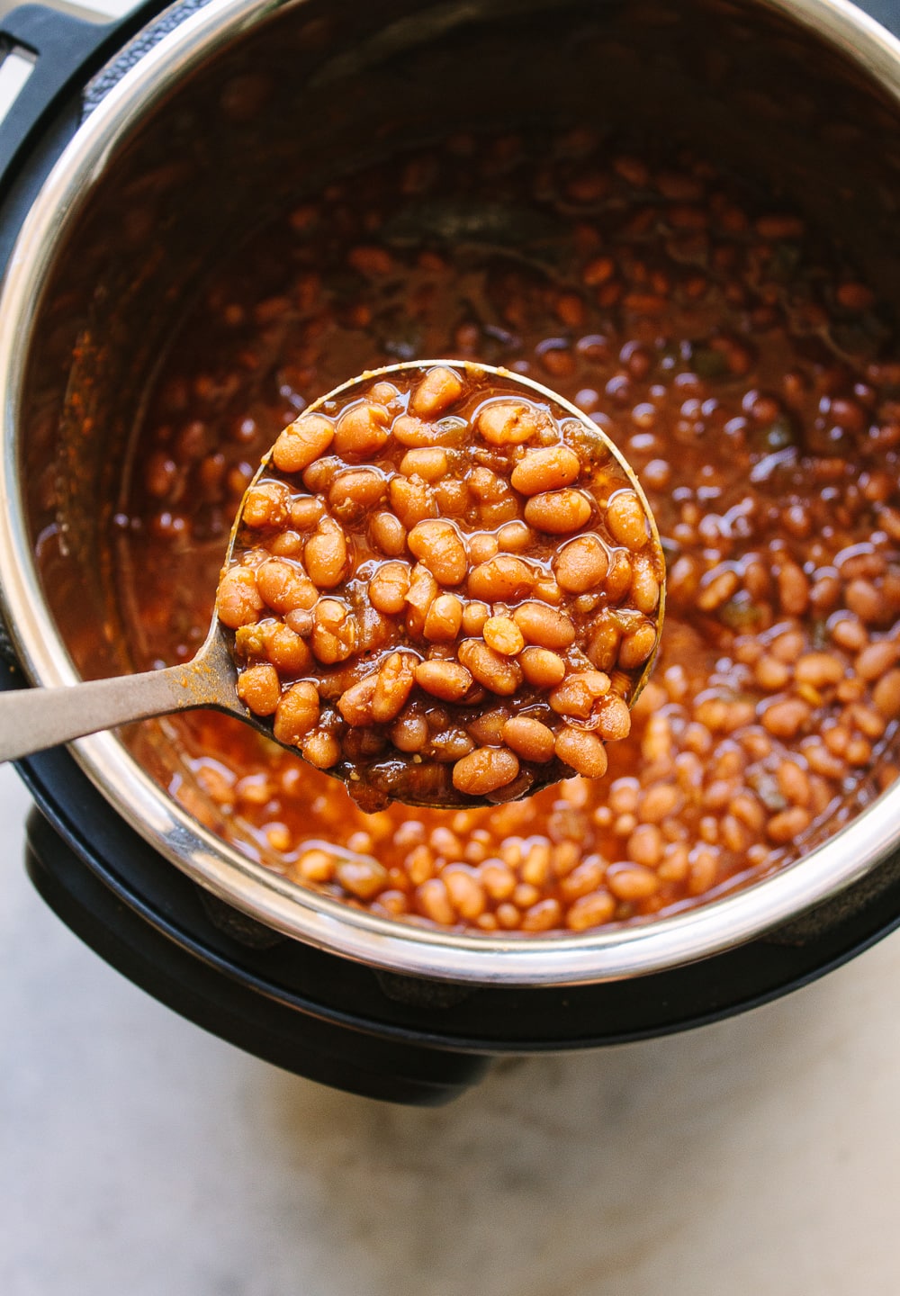 top down view of a ladle full of healthy vegan baked beans freshly cooked in an instant pot.