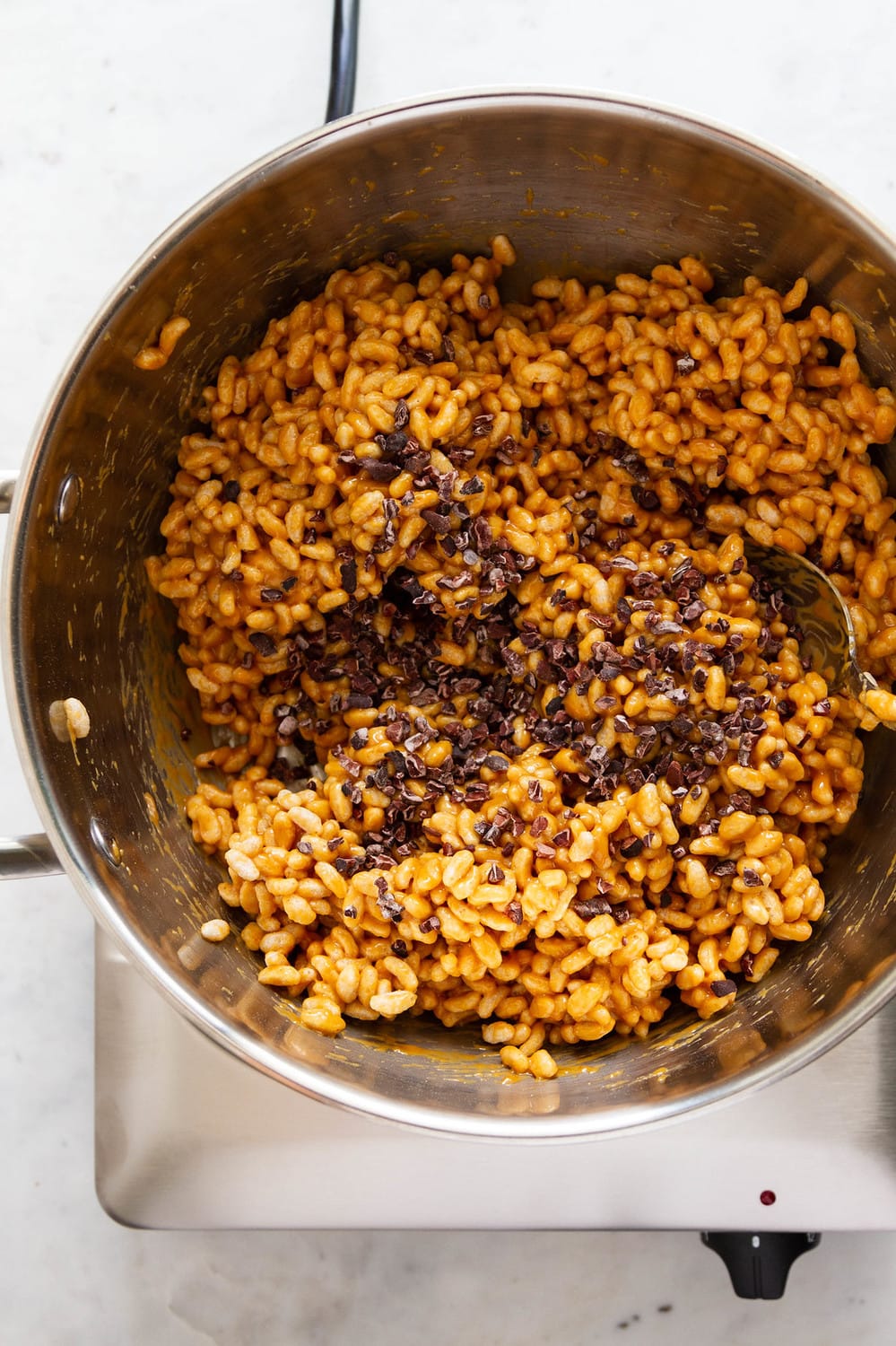 top down view of rice crispy cereal mixed with melted peanut butter and cacao nibs added