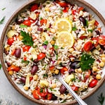 top down view of vegan Mediterranean orzo salad in a large serving bowl with spoon.