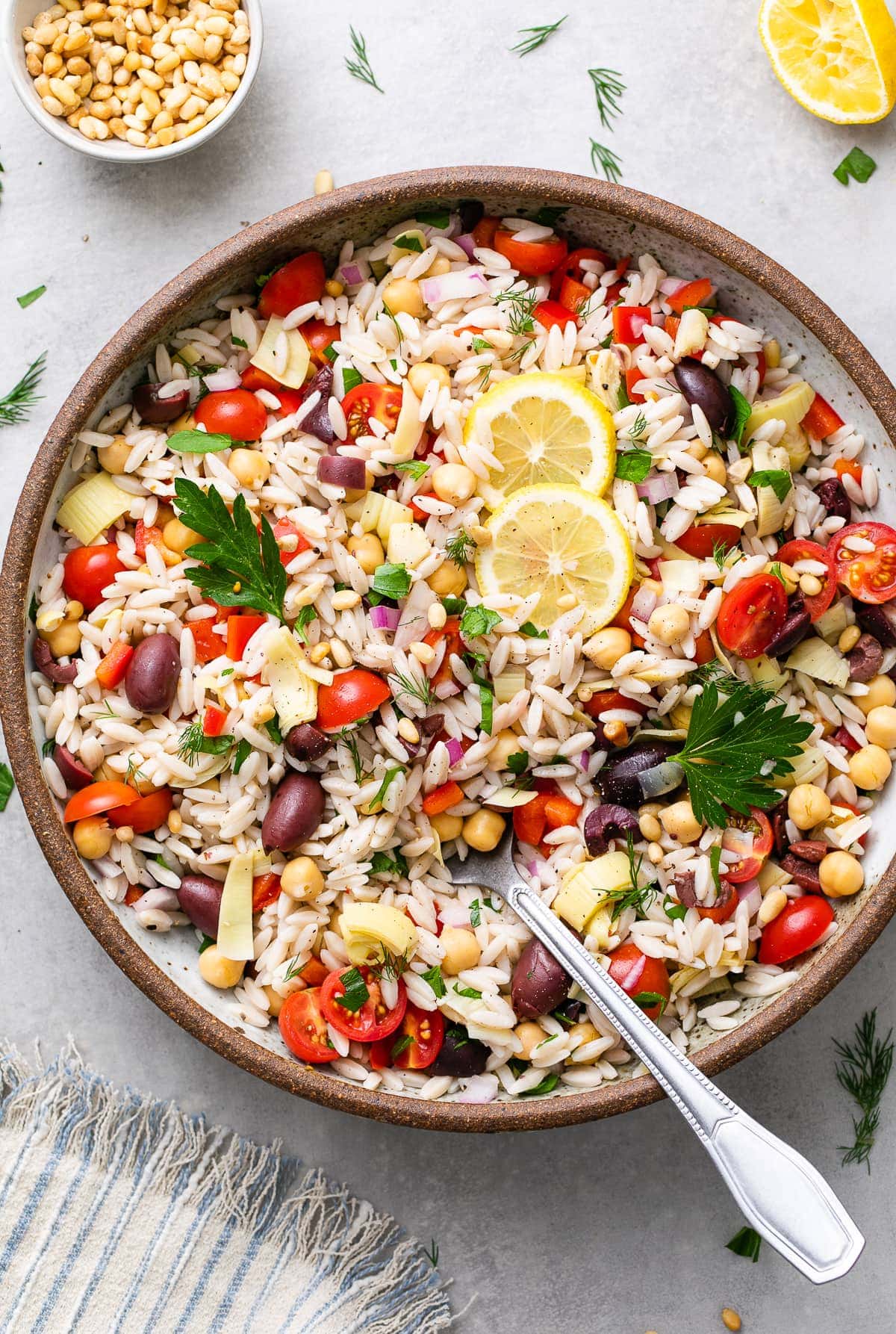 top down view of vegan Mediterranean orzo salad in a large serving bowl with spoon.