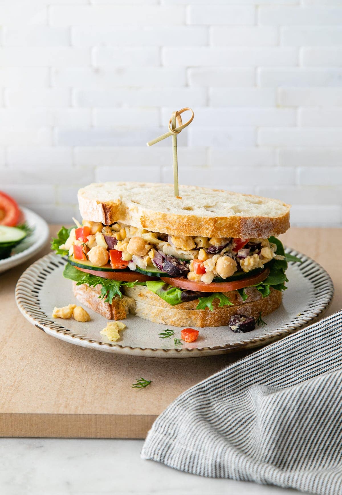 head on view of mediterranean smashed chickpea salad sandwich on a plate.