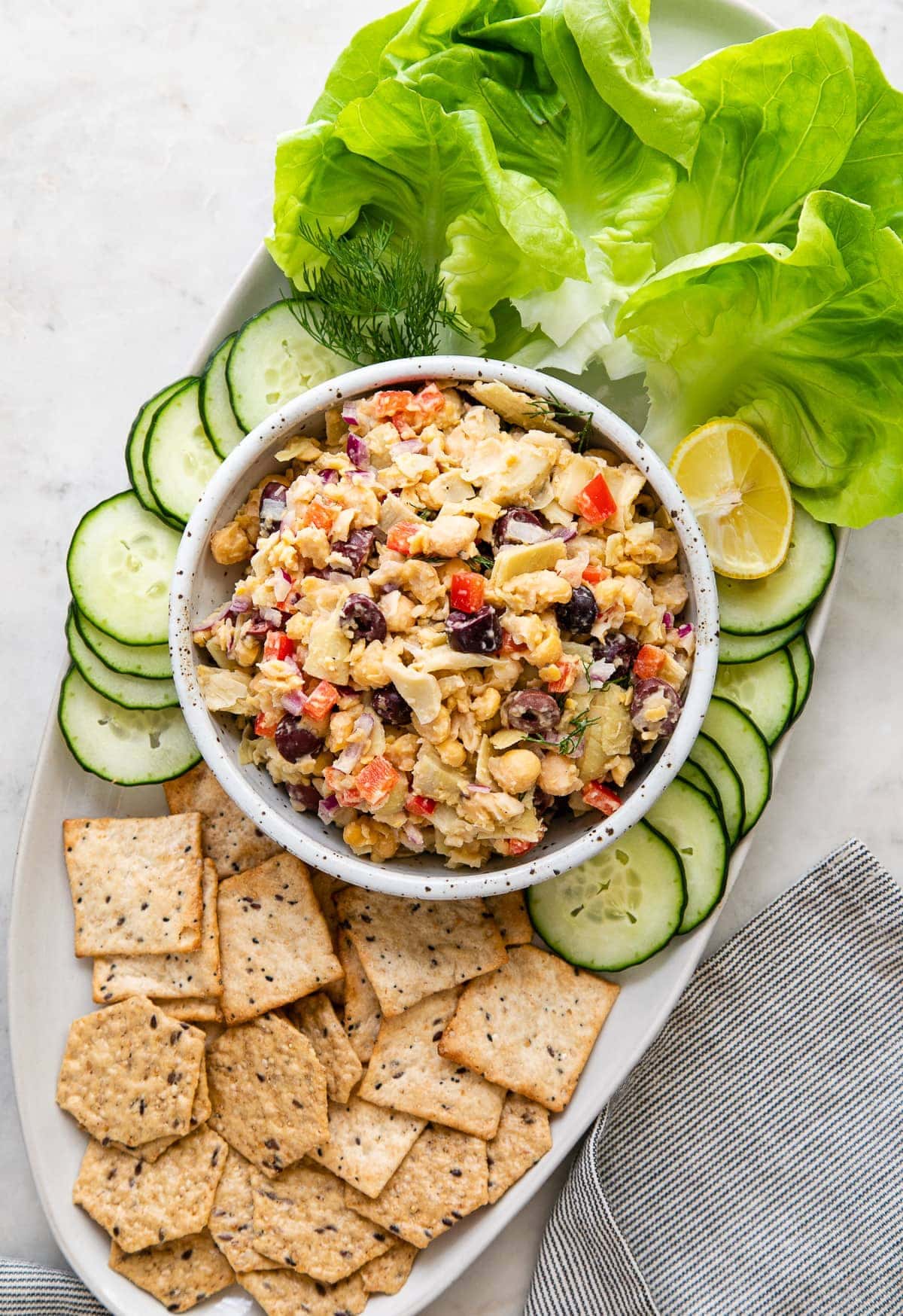 top down view of platter with Mediterranean chickpea salad with crackers, lettuce and cucumbers.