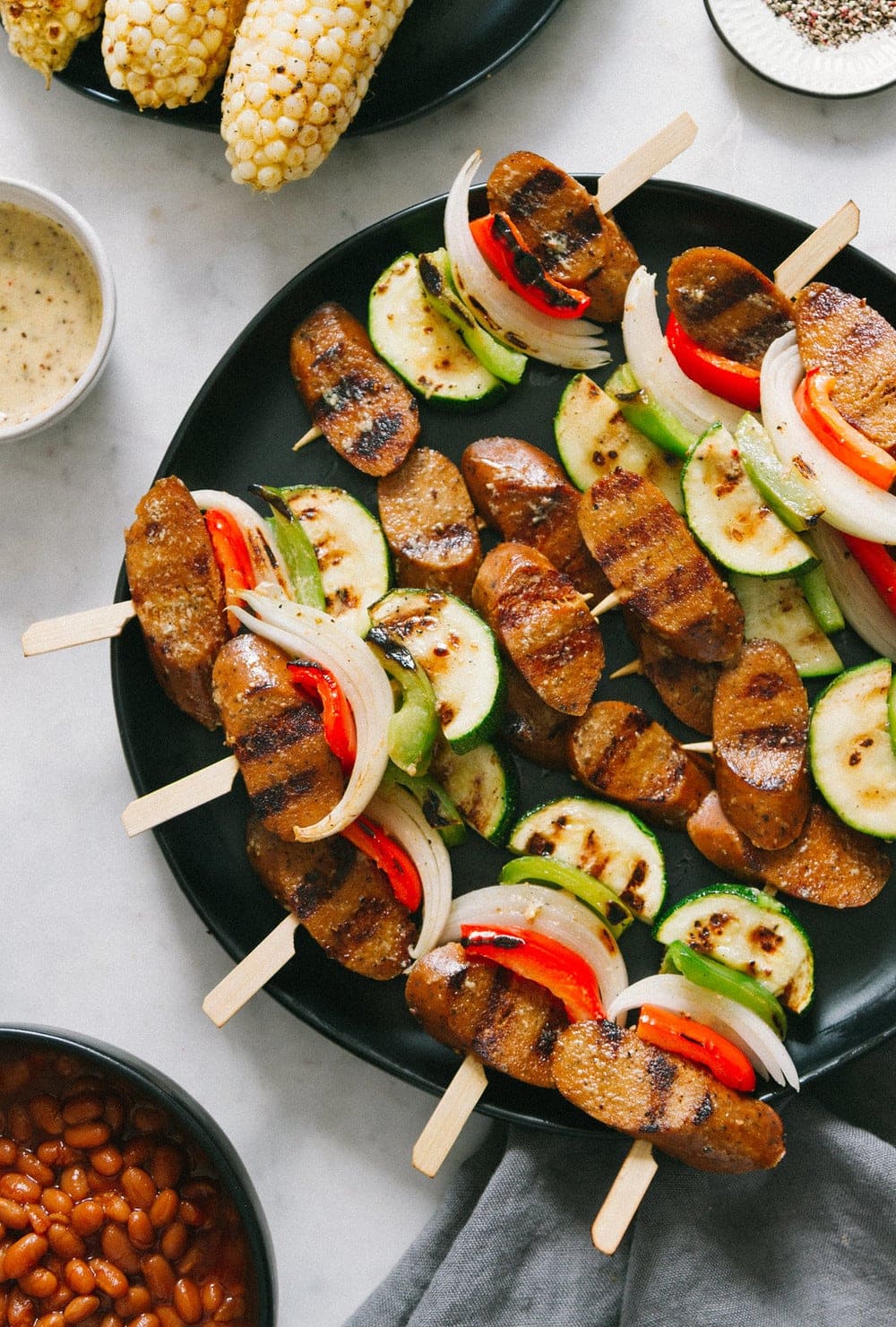top down view of grilled veggie and kielbasa skewers on a black plate