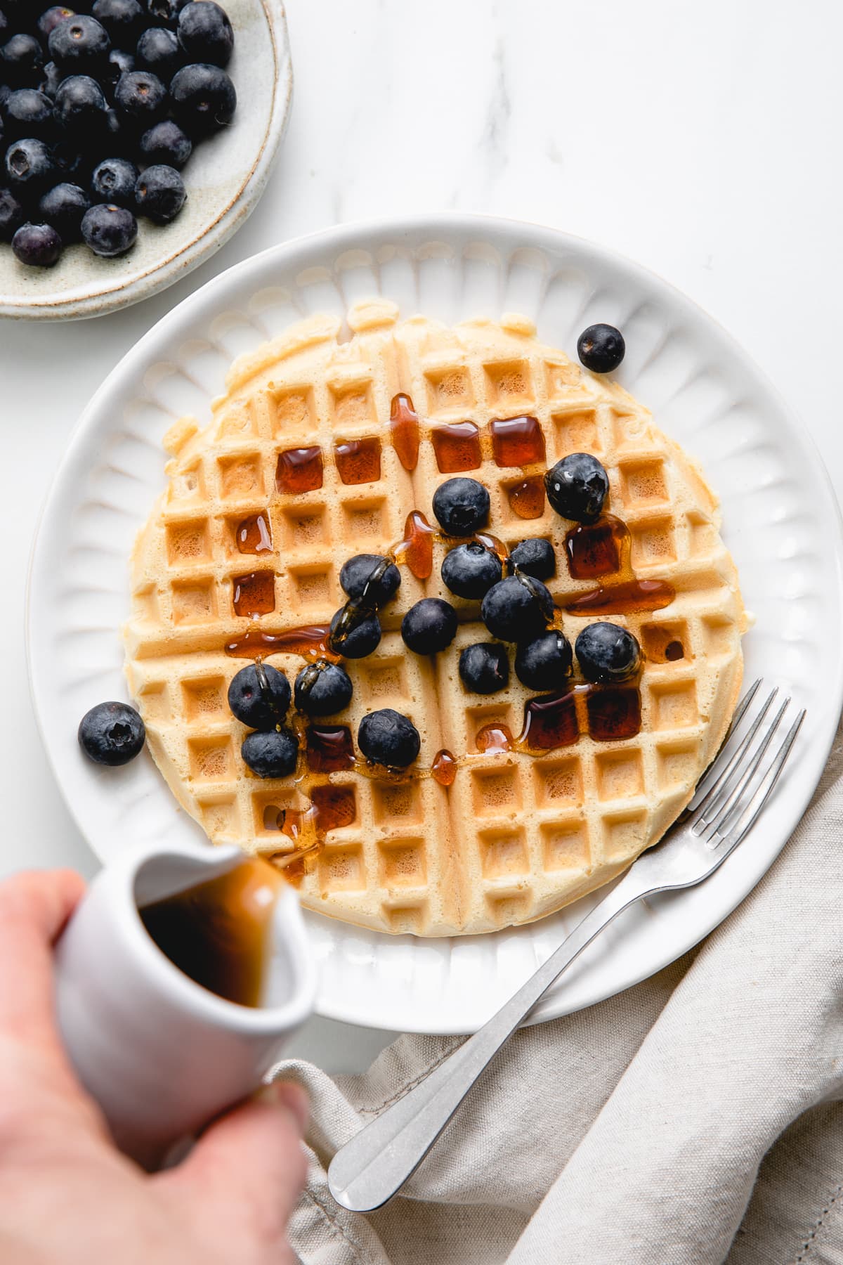 top down view of vegan waffle on a plate with syrup being poured over top.