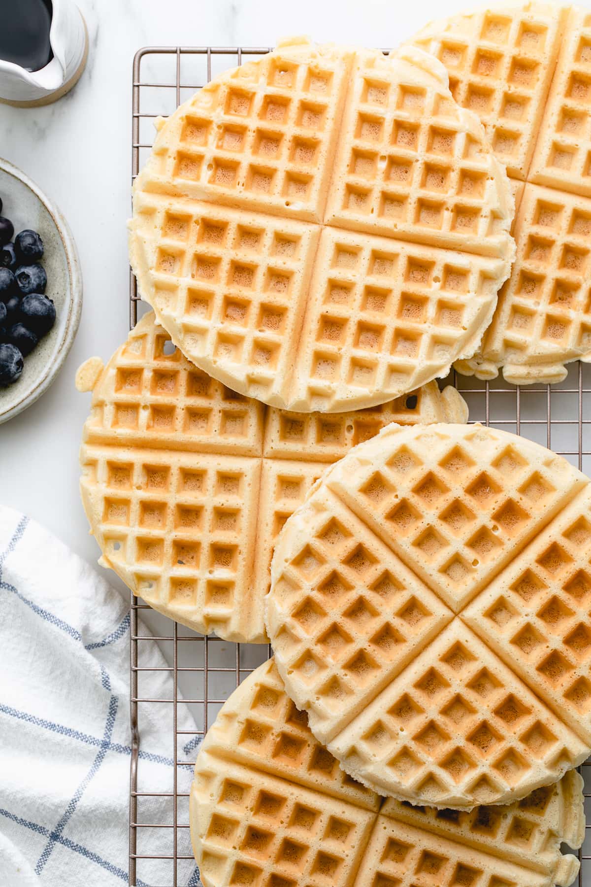 top down view of vegan waffles cooling on a wire rack with items surrounding.