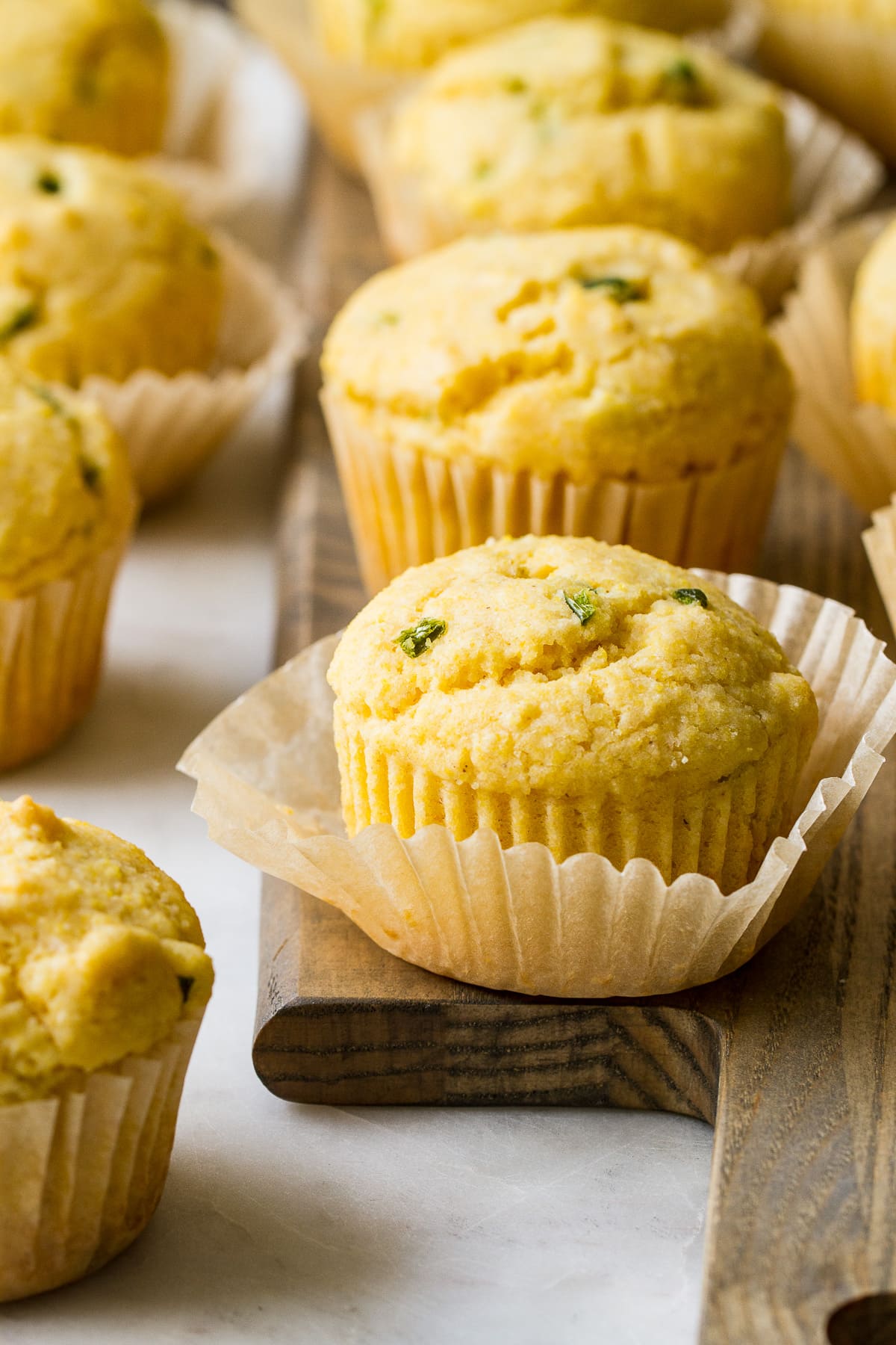 head on view of vegan corn muffins on a wooden serving board.