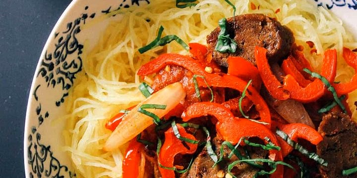 spaghetti squash with peppers, onion and sausage in a white bowl
