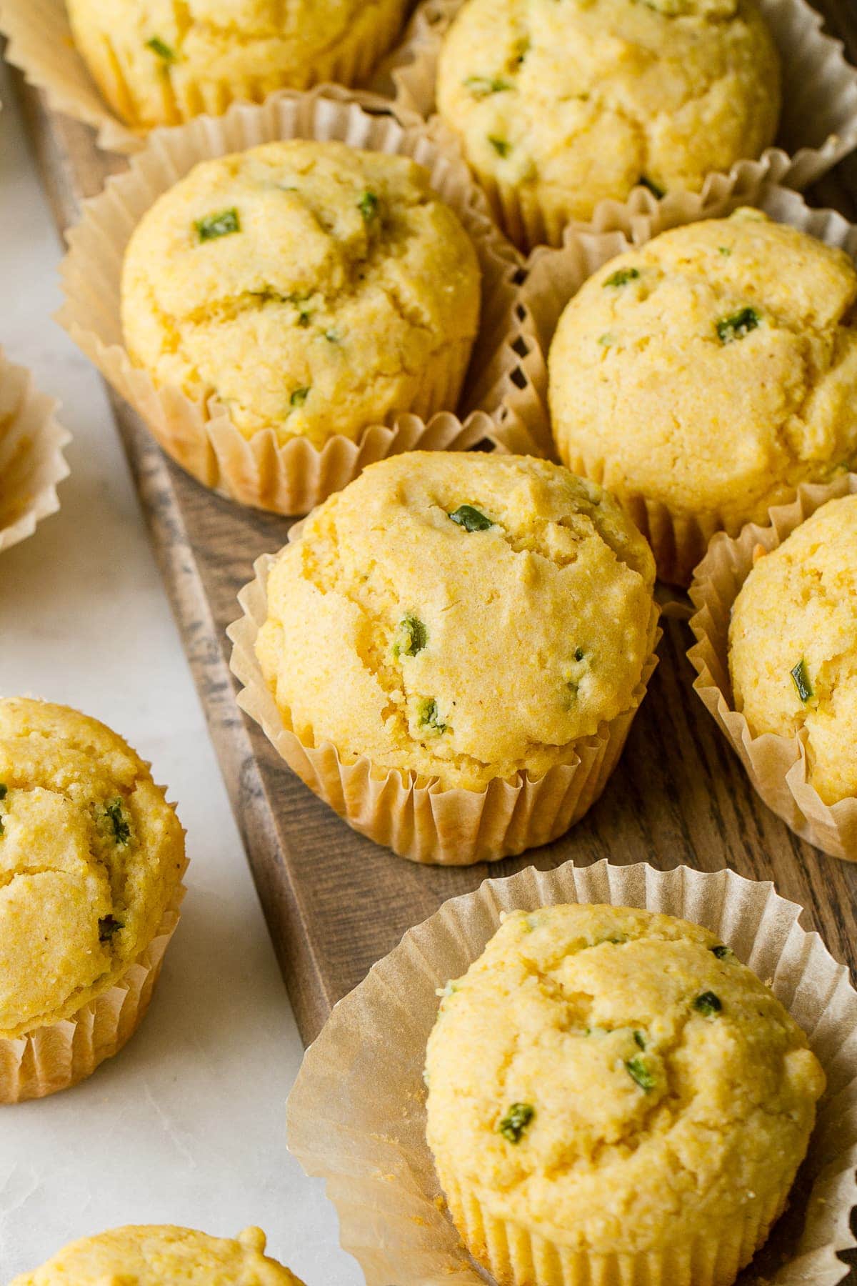 side angle view of vegan corn muffins on a wooden serving board.