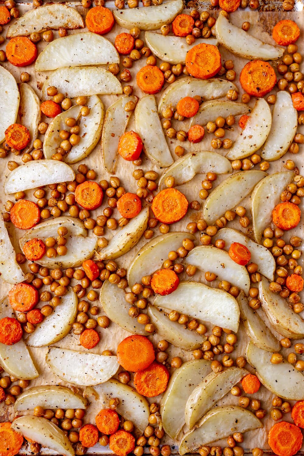 top down view of roasted chickpeas, potatoes and carrots on a rimmed baking sheet.