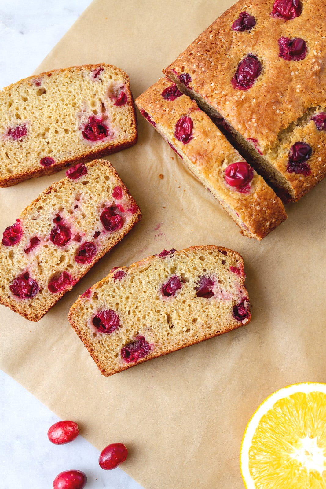 top down view of sliced cranberry orange bread on parchment paper.
