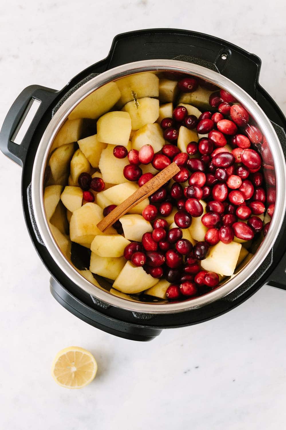 apples and cranberries in and instant pot with a cinnamon stick
