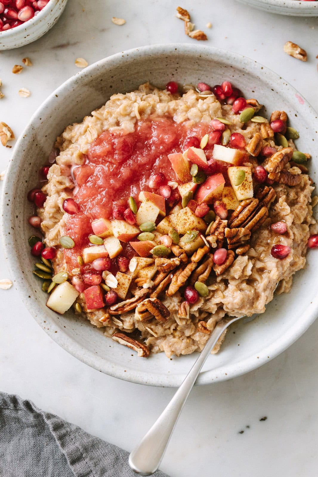 up close view of cinnamon oatmeal in a bowl with toppings and items surrounding.