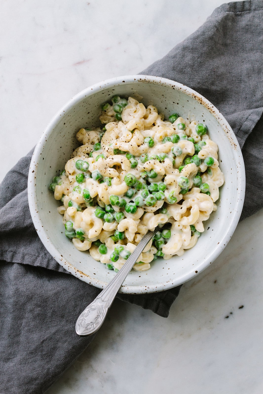 top down view of a bowl with a serving of easy vegan mac and cheese with peas.