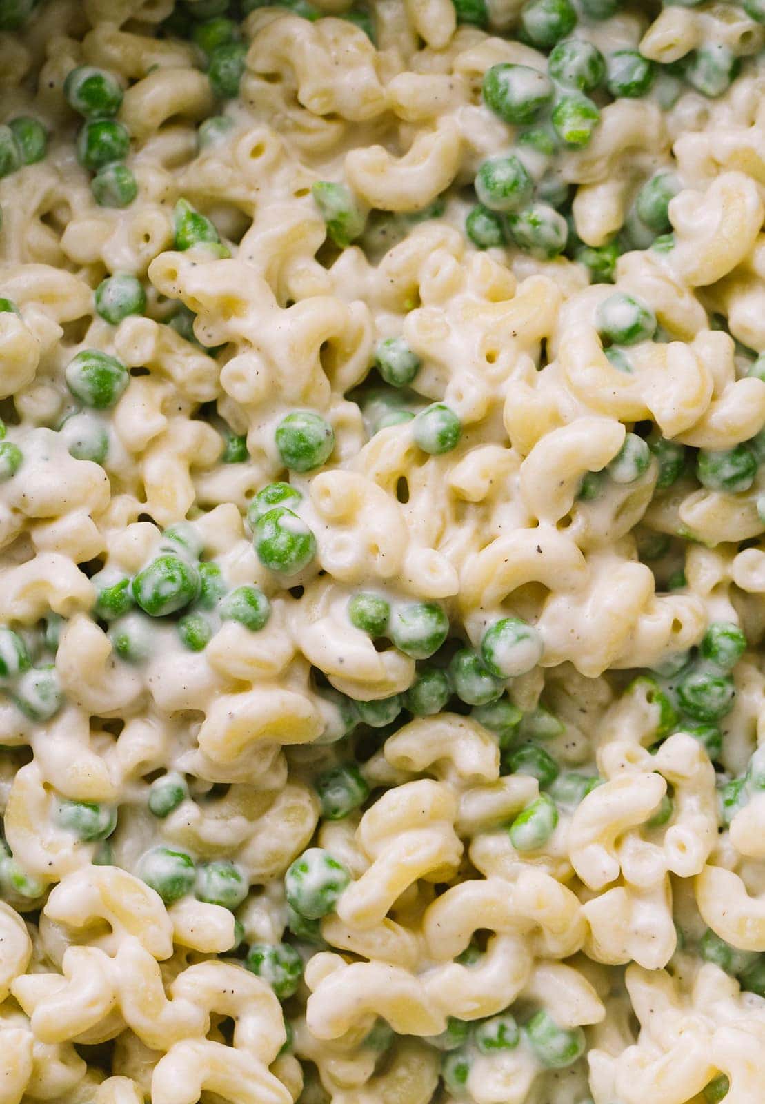 up close view of white vegan mac and cheese with peas.