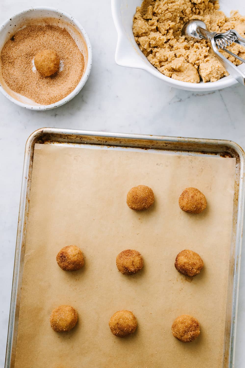 vegan snickerdoodles being rolled and dipped in cinnamon sugar