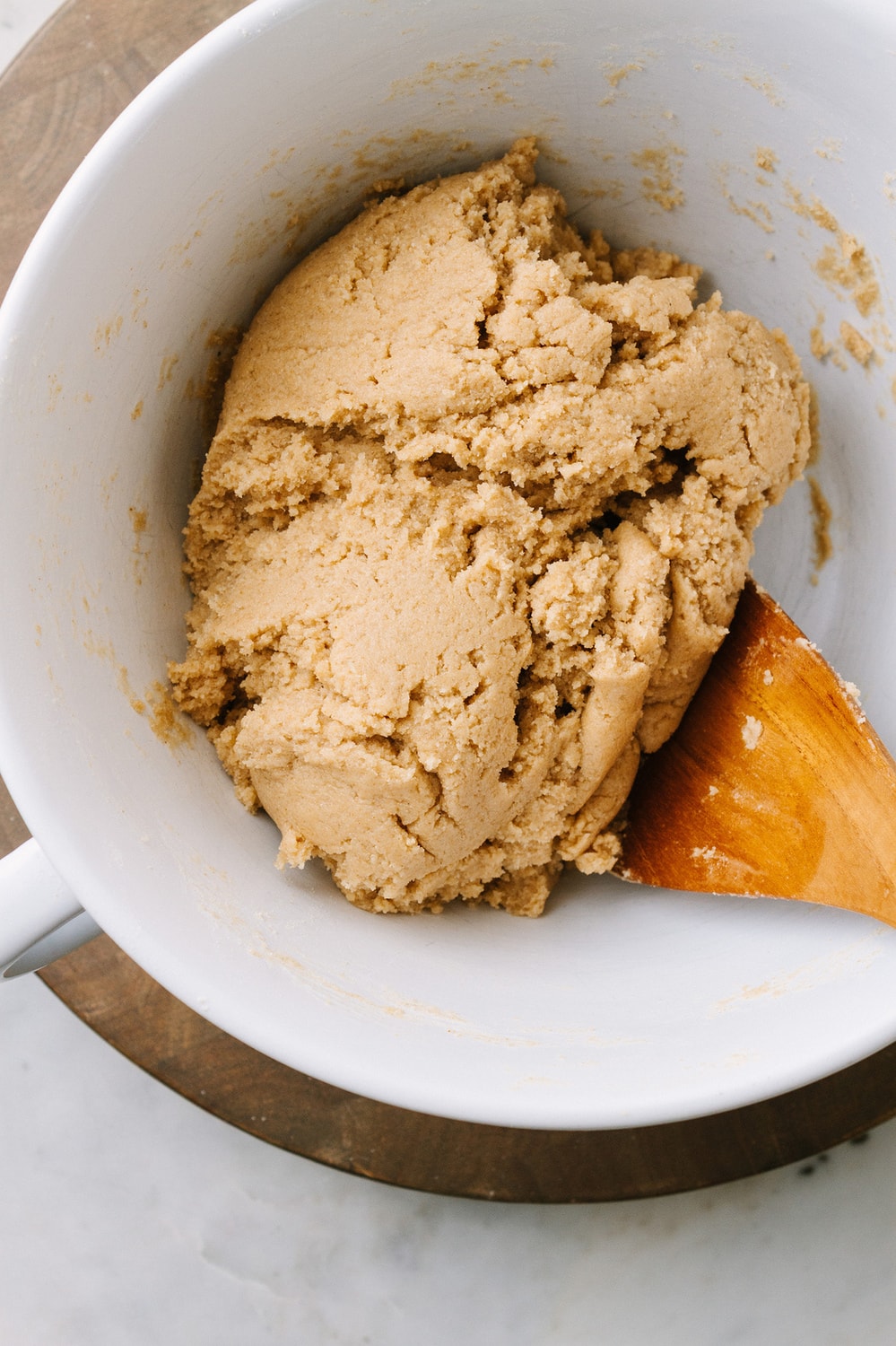 vegan snickerdoodles dough in a mixing bowl with wooden spoon