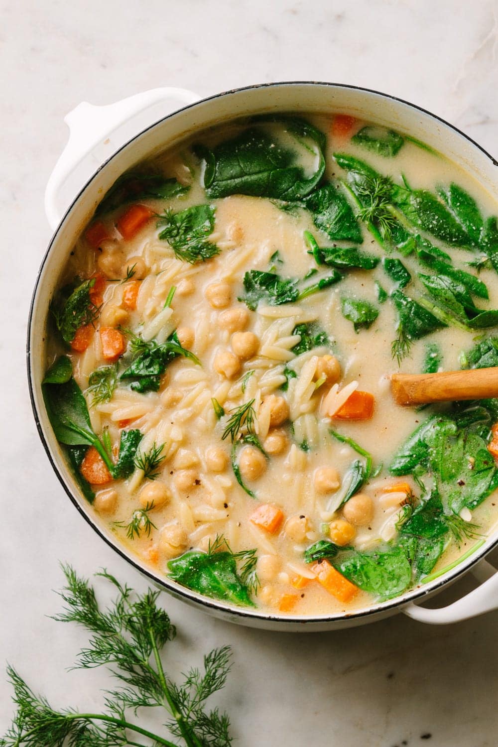 top down view of creamy lemon chickpea orzo soup in a pot.