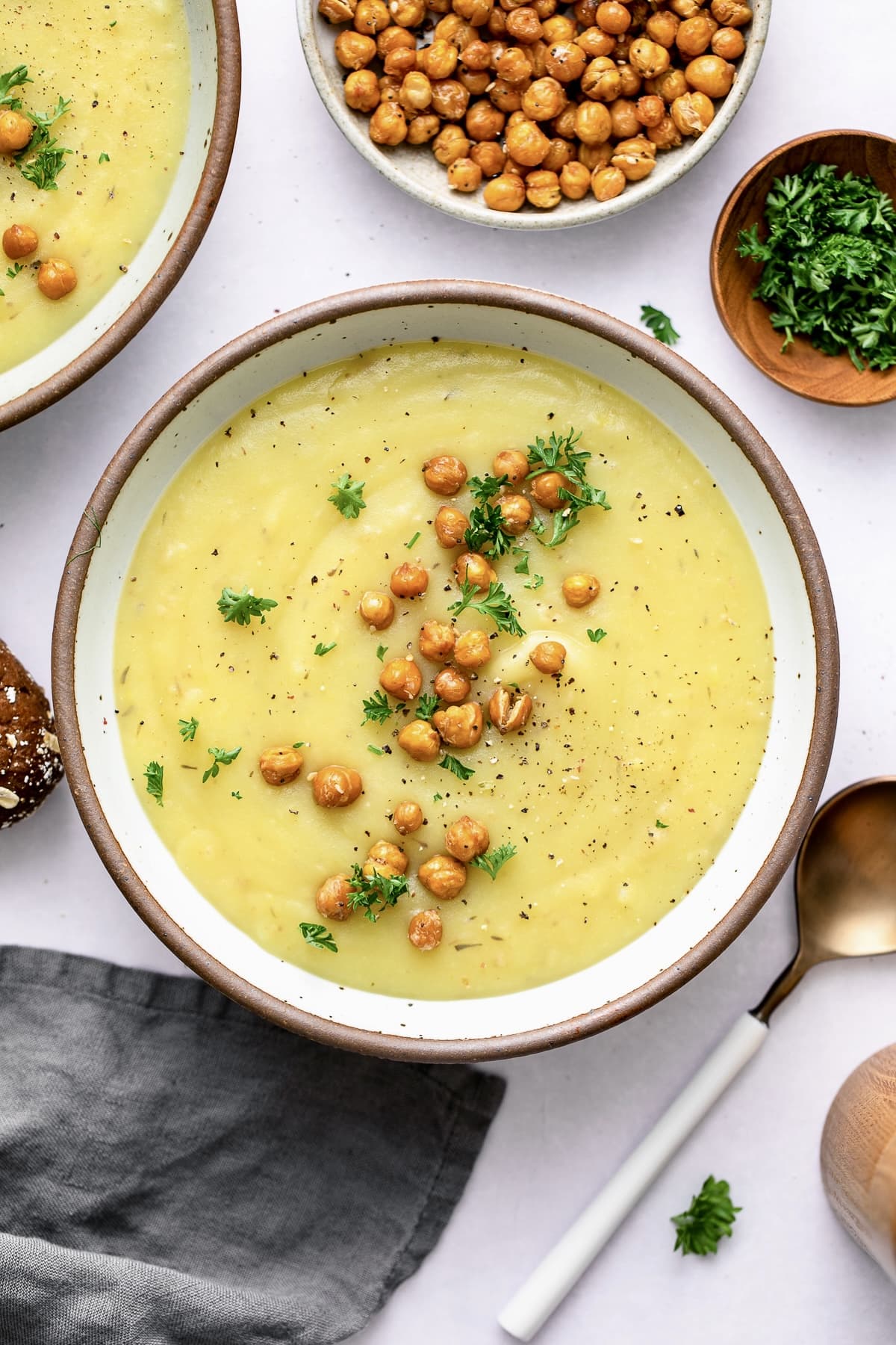 top down view of creamy vegan potato leek soup in a bowl with items surrounding.