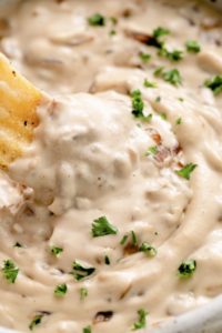 creamy caramelized vegan french onion dip in a bowl with chip