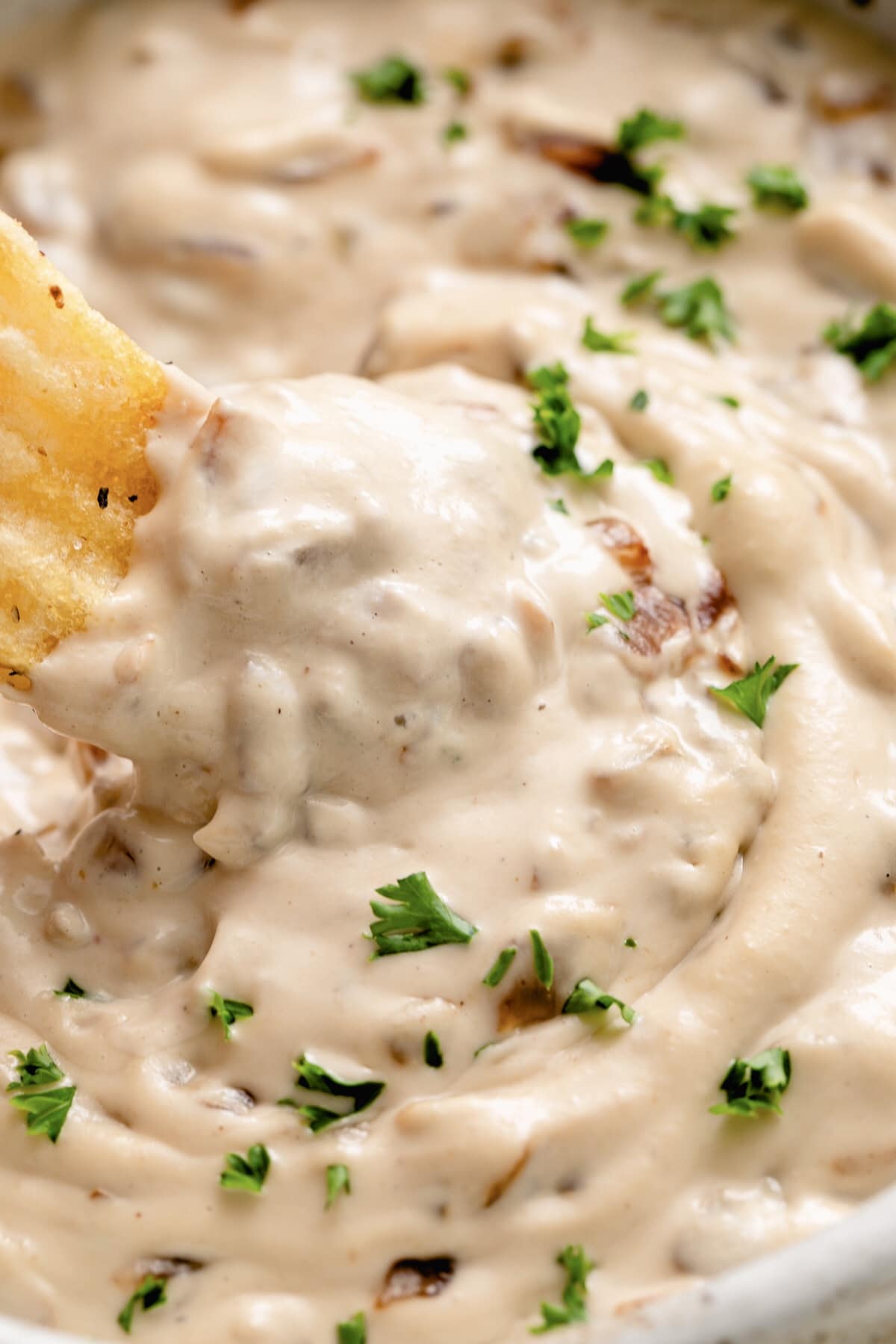 creamy caramelized vegan french onion dip in a bowl with chip