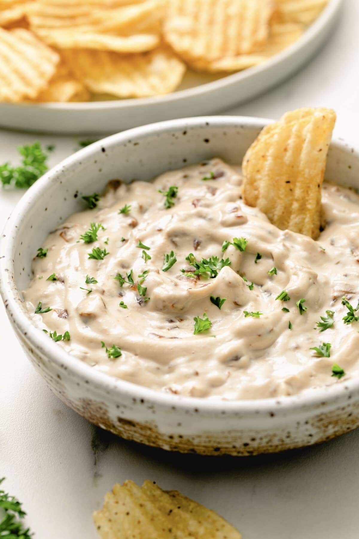 creamy caramelized vegan french onion dip in a bowl with chips