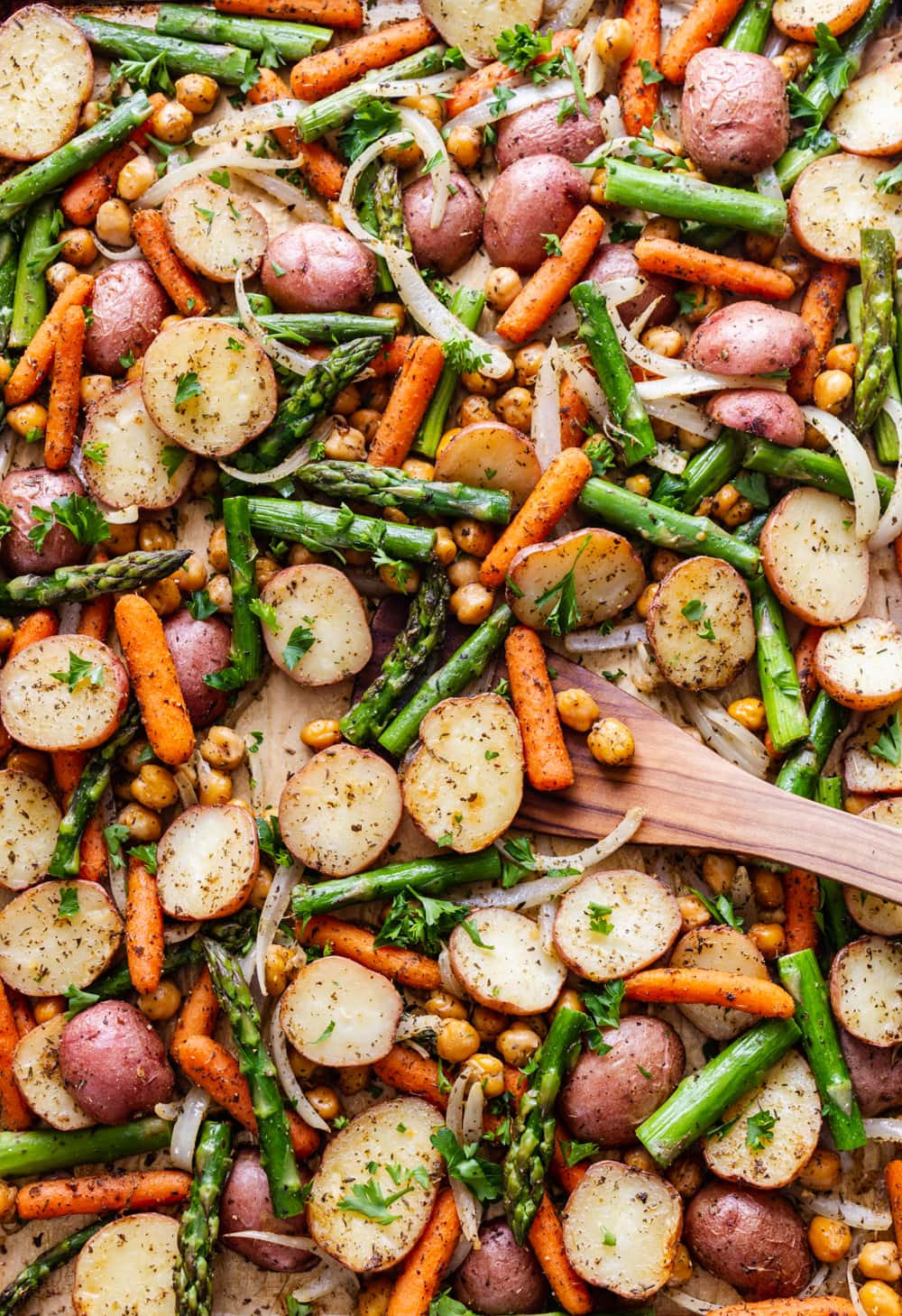 freshly roasted asparagus, potato and chickpea sheet pan dinner with a wooden spatula