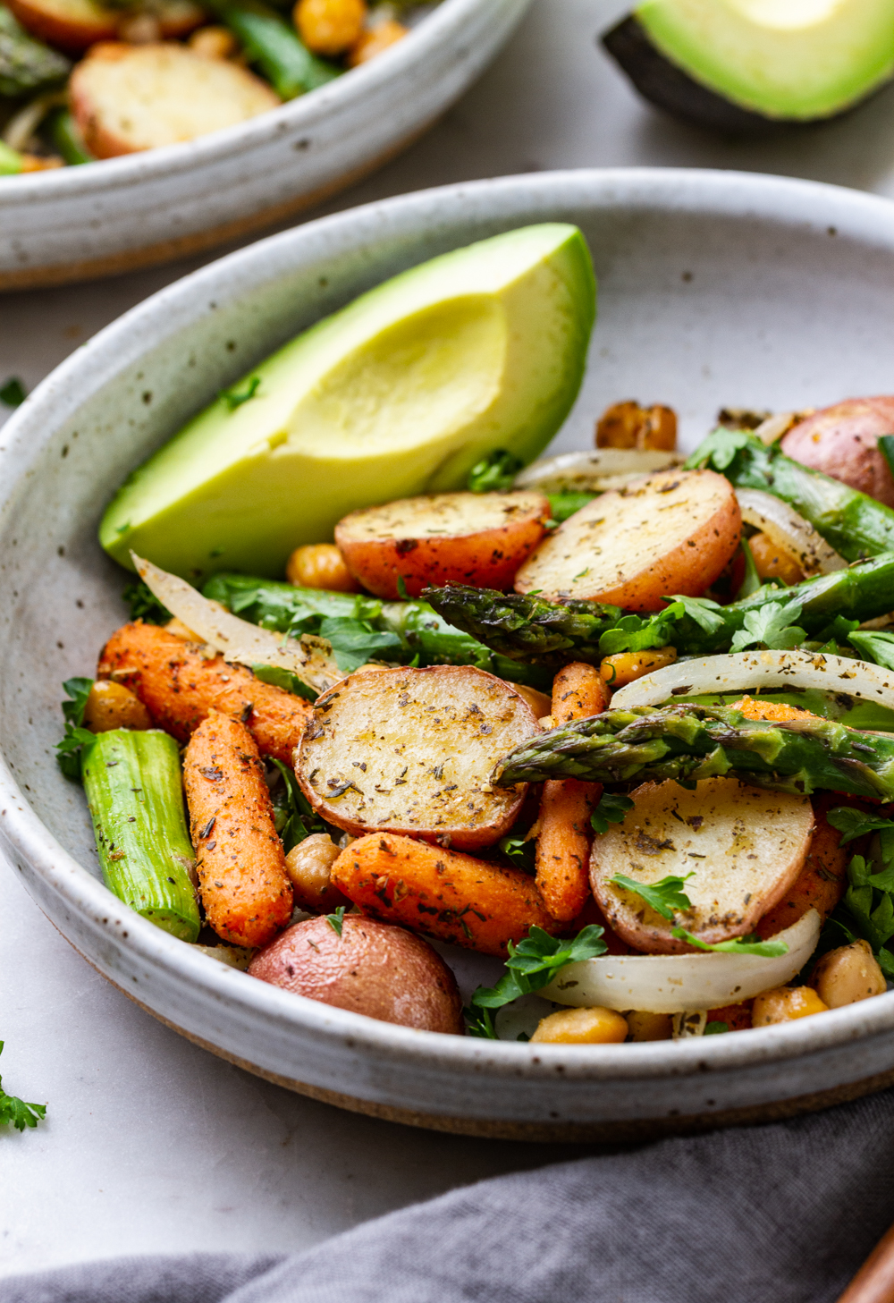 side shot of bowl with roasted asparagus, potato + chickpea with avocado 