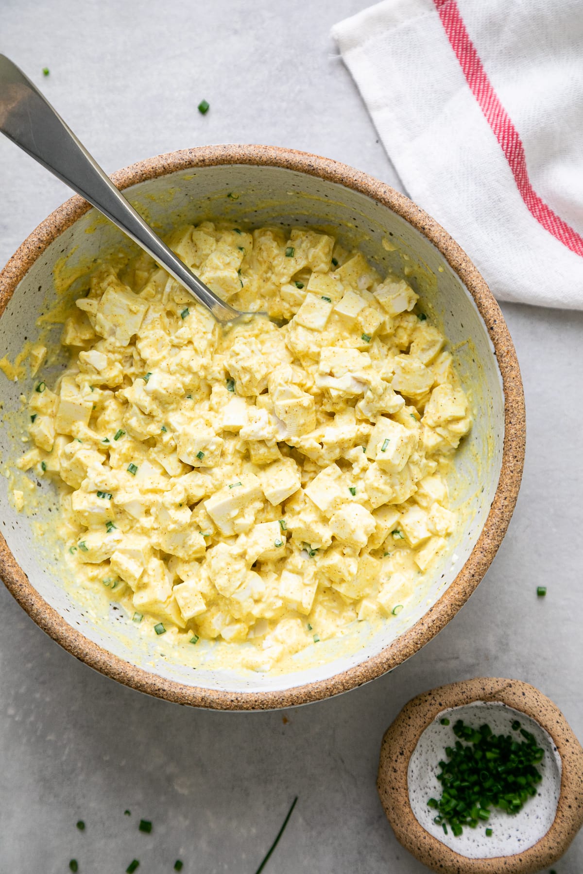 top down view of freshly made vegan egg salad in a bowl with items surrounding.