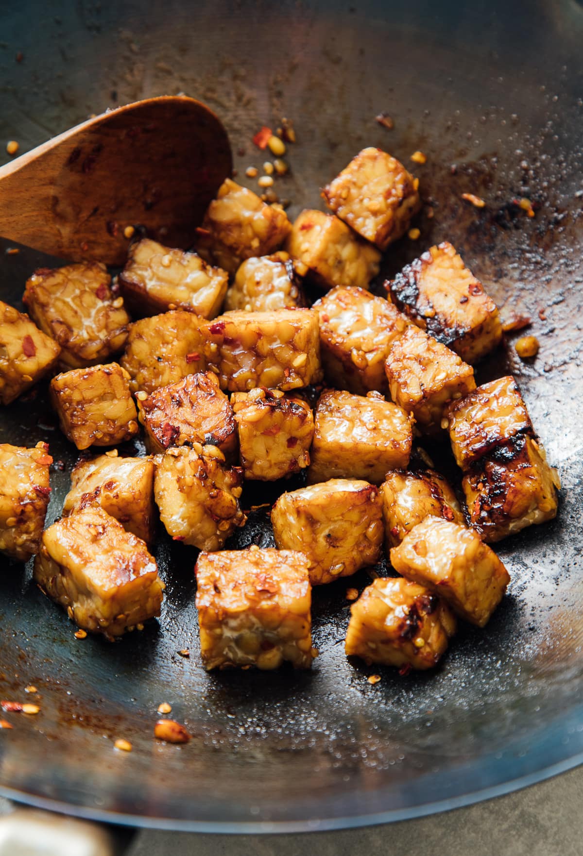 side angle view of stir fried tempeh in a wok.