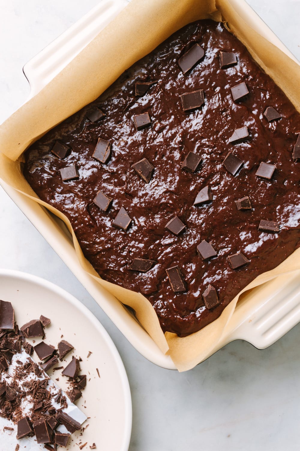 brownie batter in baking dish topped with chocolate chunks