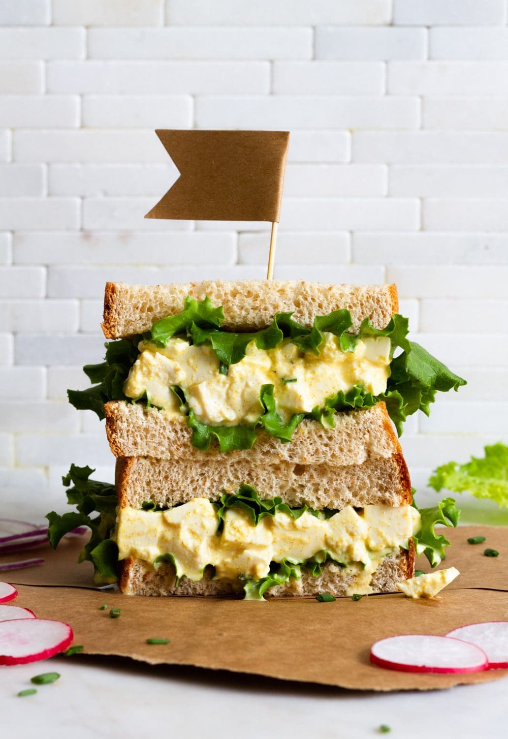 vegan egg salad sandwich with leafy greens sliced in half and stacked.