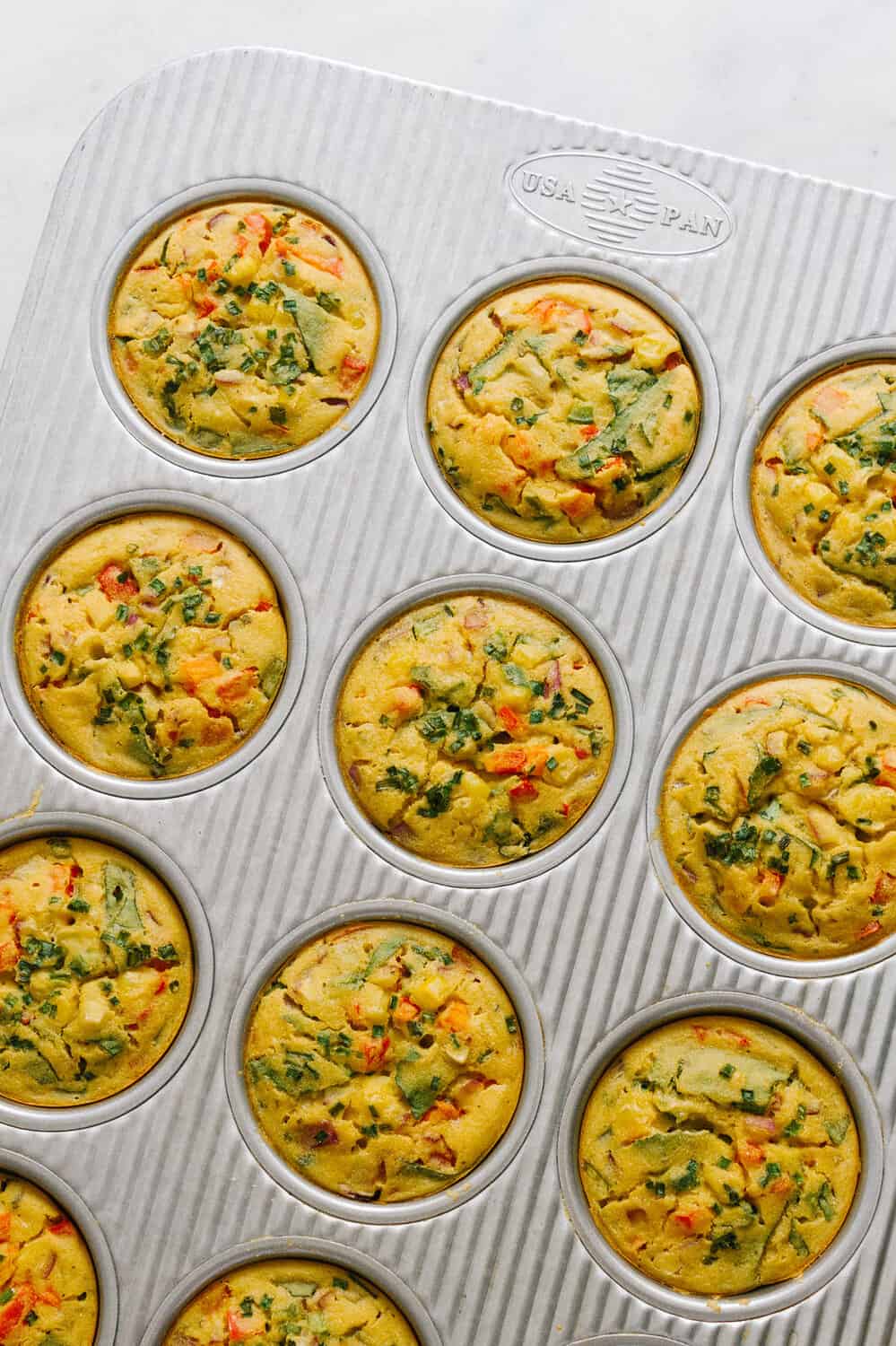 top down view of freshly baked mini chickpea frittatas in a muffin tin.