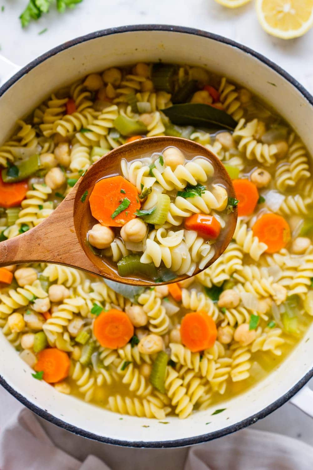 top down view of chickpea noodle soup in a pot with ladle. 