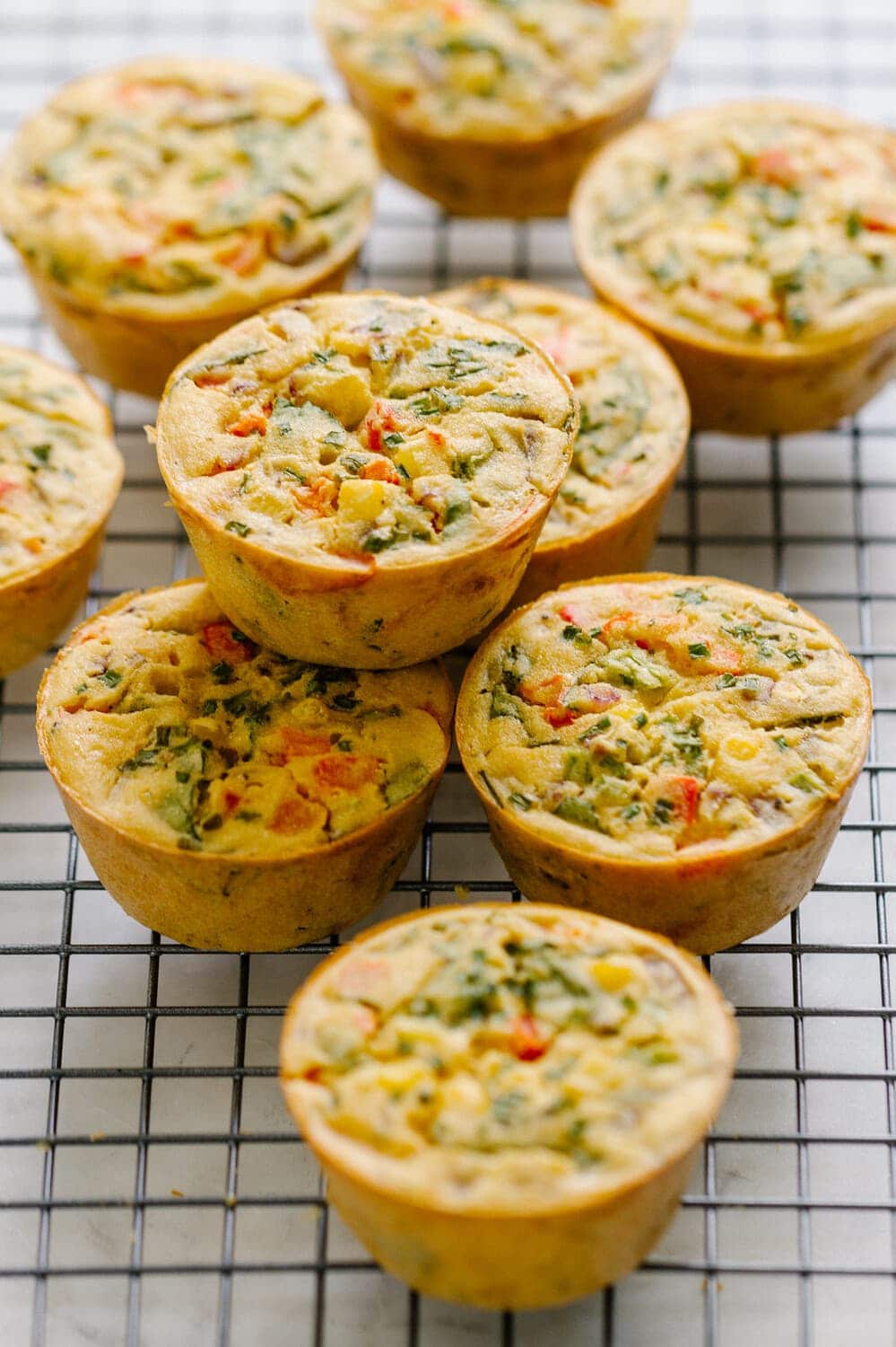 side angle view of mini chickpea flour frittata muffins cooking on a wire rack.