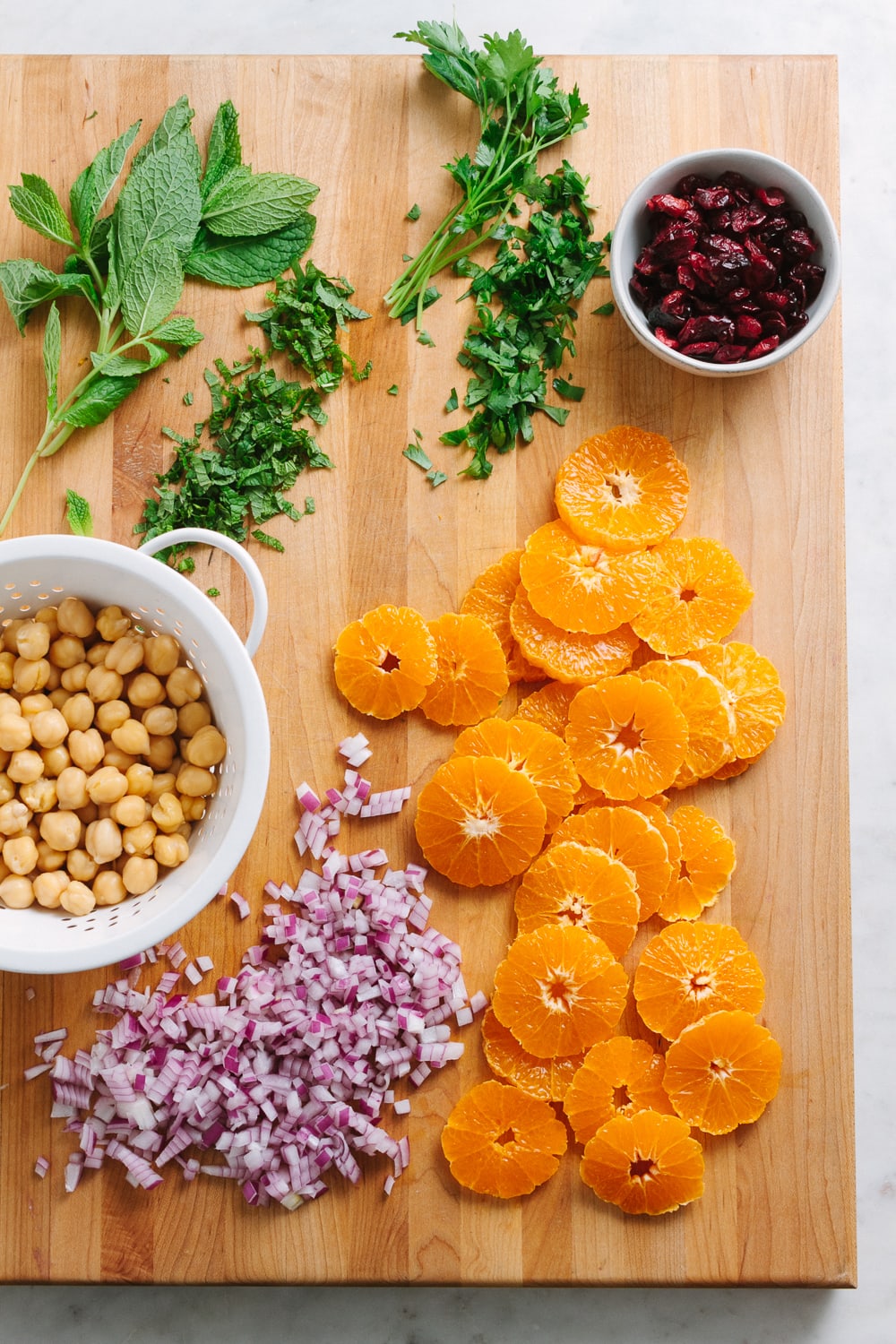 top down view of wooden cutting board with prepped salad ingredients.