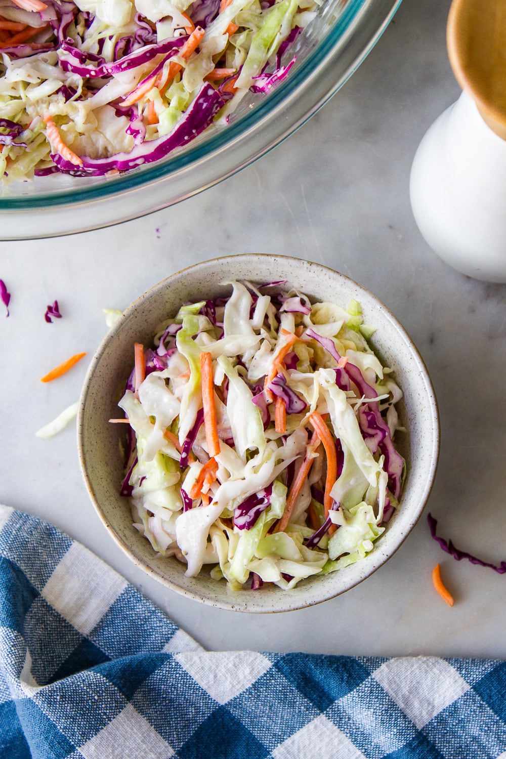 top down view of a small bowl with a serving of creamy vegan coleslaw with items surrounding.