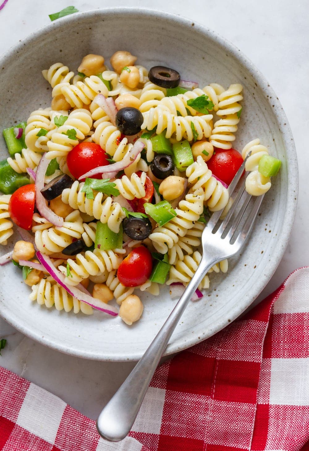 top down view of a serving of easy vegan pasta in a bowl with fork and red and white checked napkin.