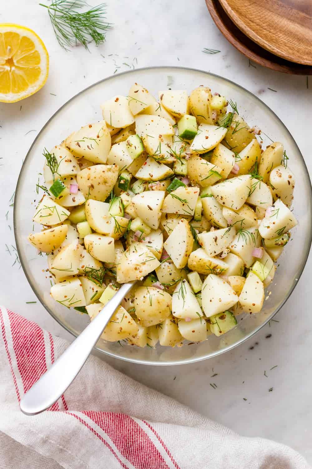 top down view of a glass mixing bowl with freshly mixed german potato salad.