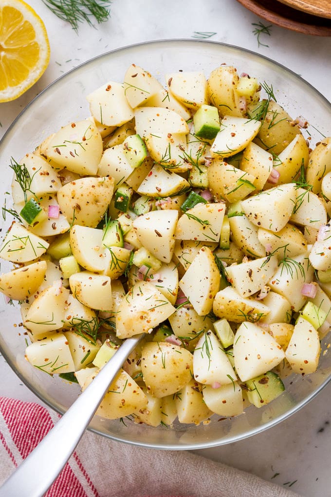 top down view of a glass mixing bowl with freshly mixed german potato salad.