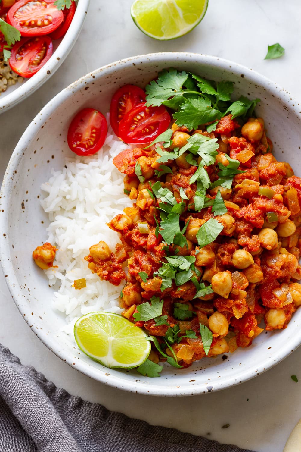 top down view of healthy chana masala in a bowl with rice, lime and cilantro.
