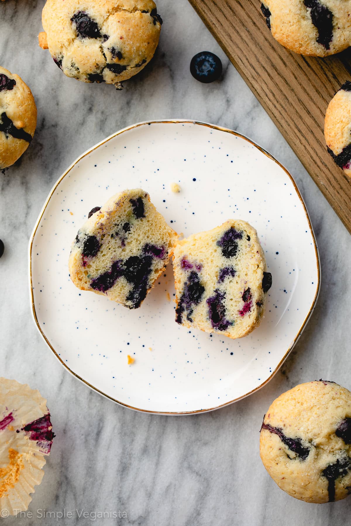 top down view of muffin split open on a small plate with other muffins surrounding.