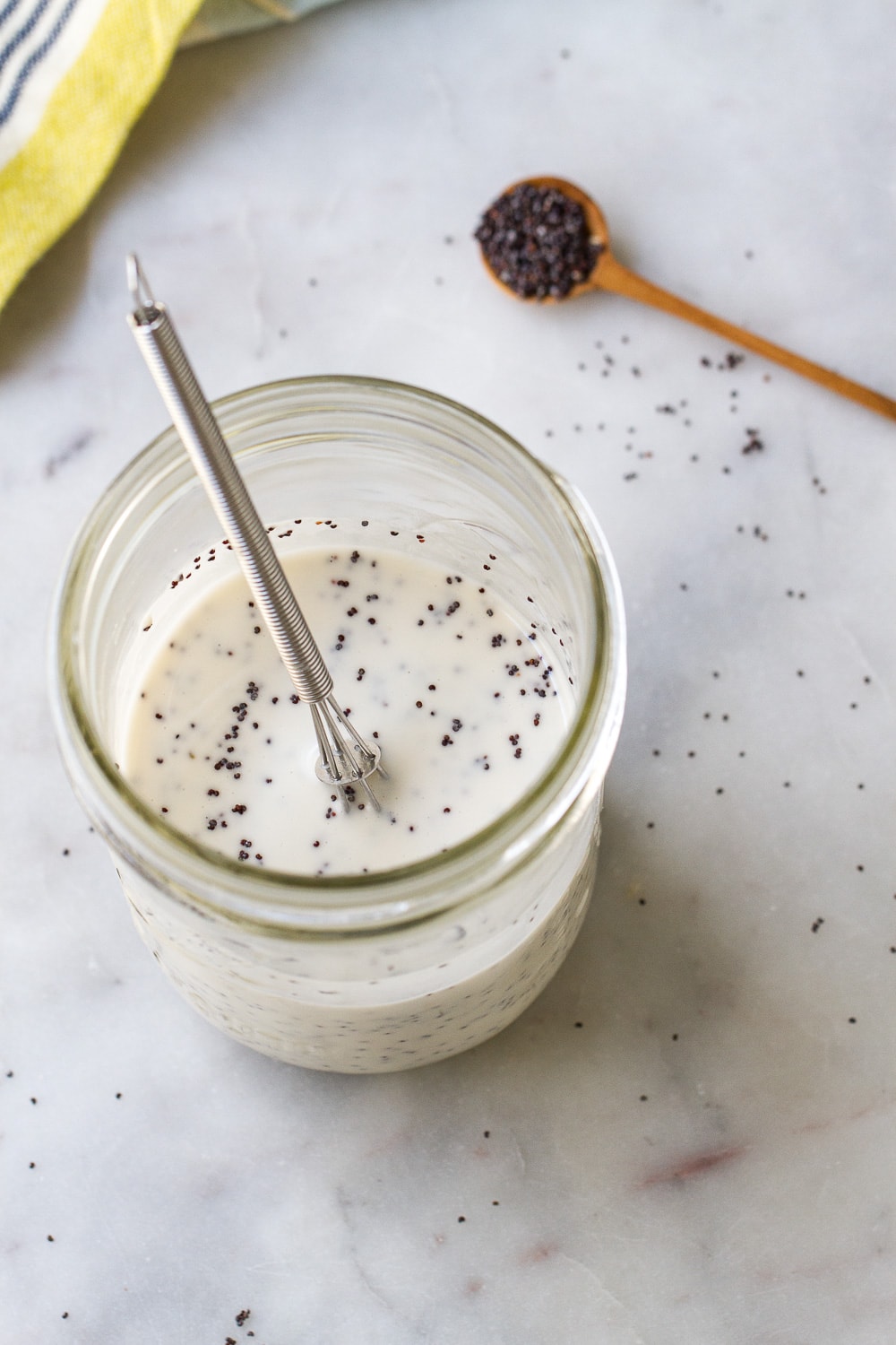 side angle view of creamy poppyseed dressing in a glass mason jar.