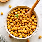 top down view of bowl full of crispy roasted chickpeas with wooden spoon for scooping.