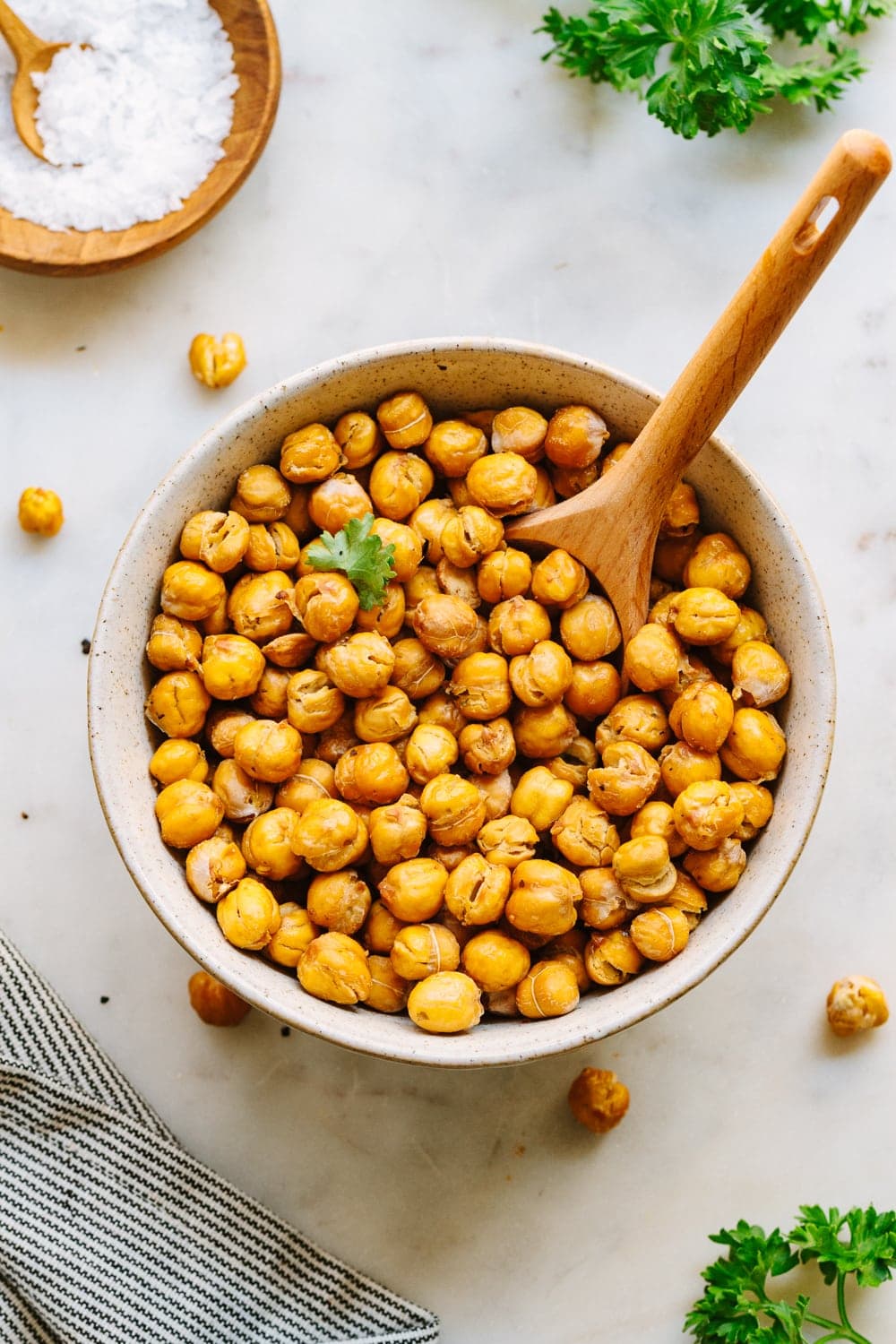 top down view of bowl full of crispy roasted chickpeas with wooden spoon for scooping.