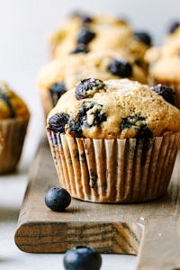 head on shot of vegan blueberry muffins on a wooden serving board.