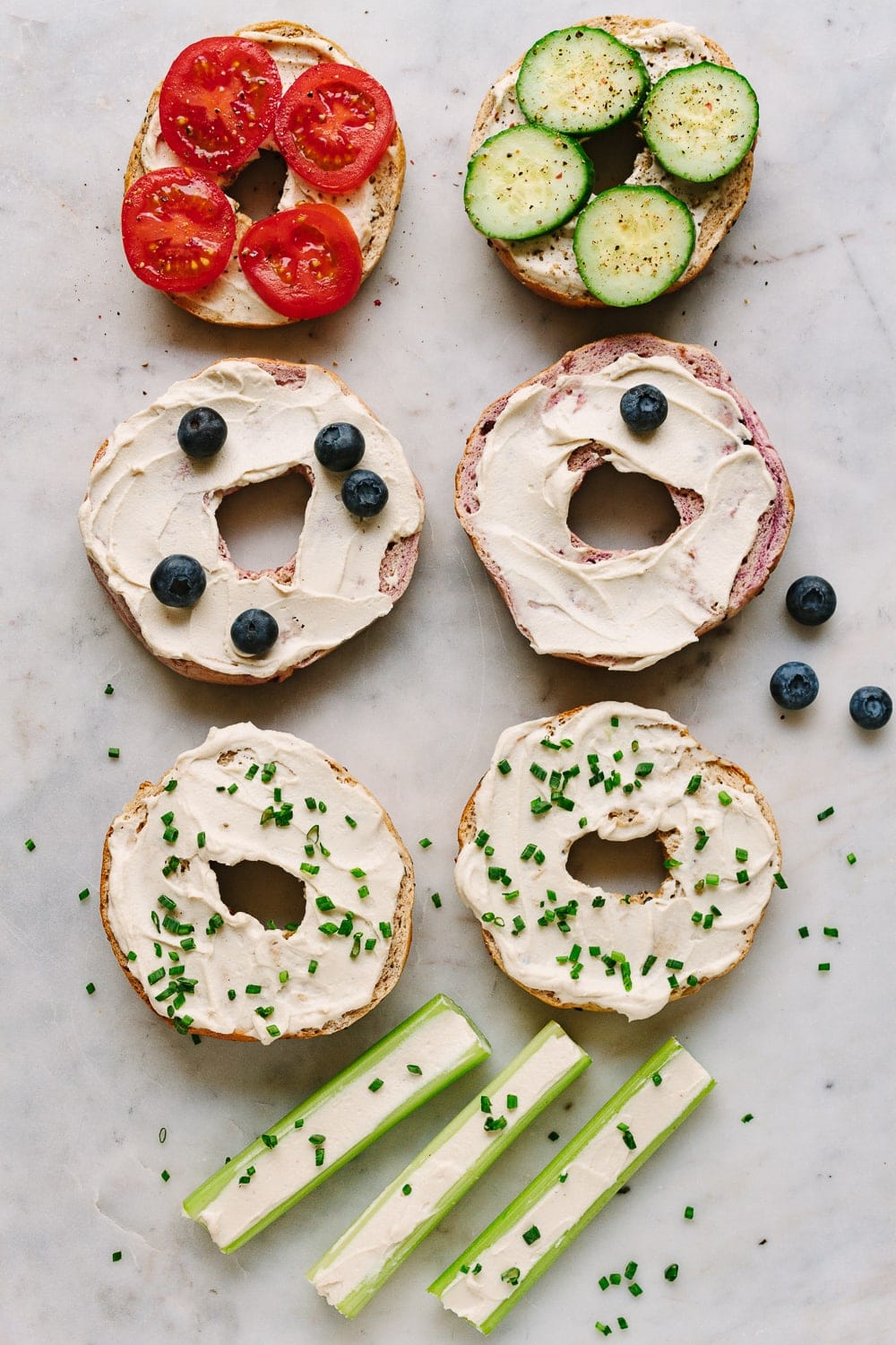 top view of an assortment of bagels topped with vegan cream cheese and various toppings.