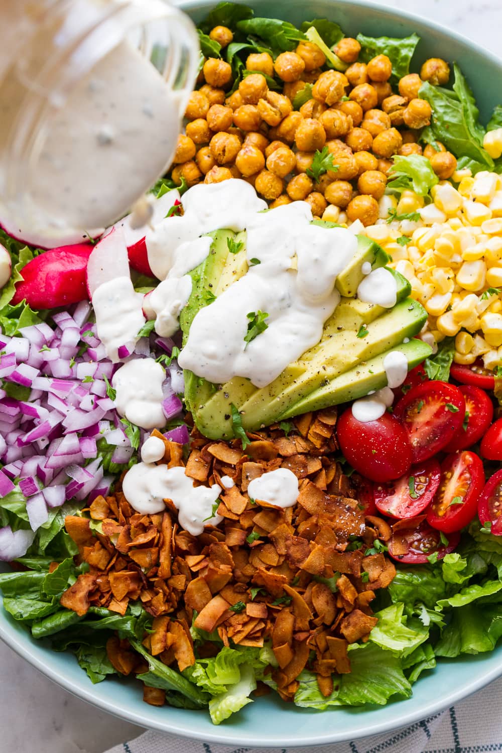 side angle view of vegan ranch being drizzled on easy vegan cobb salad.