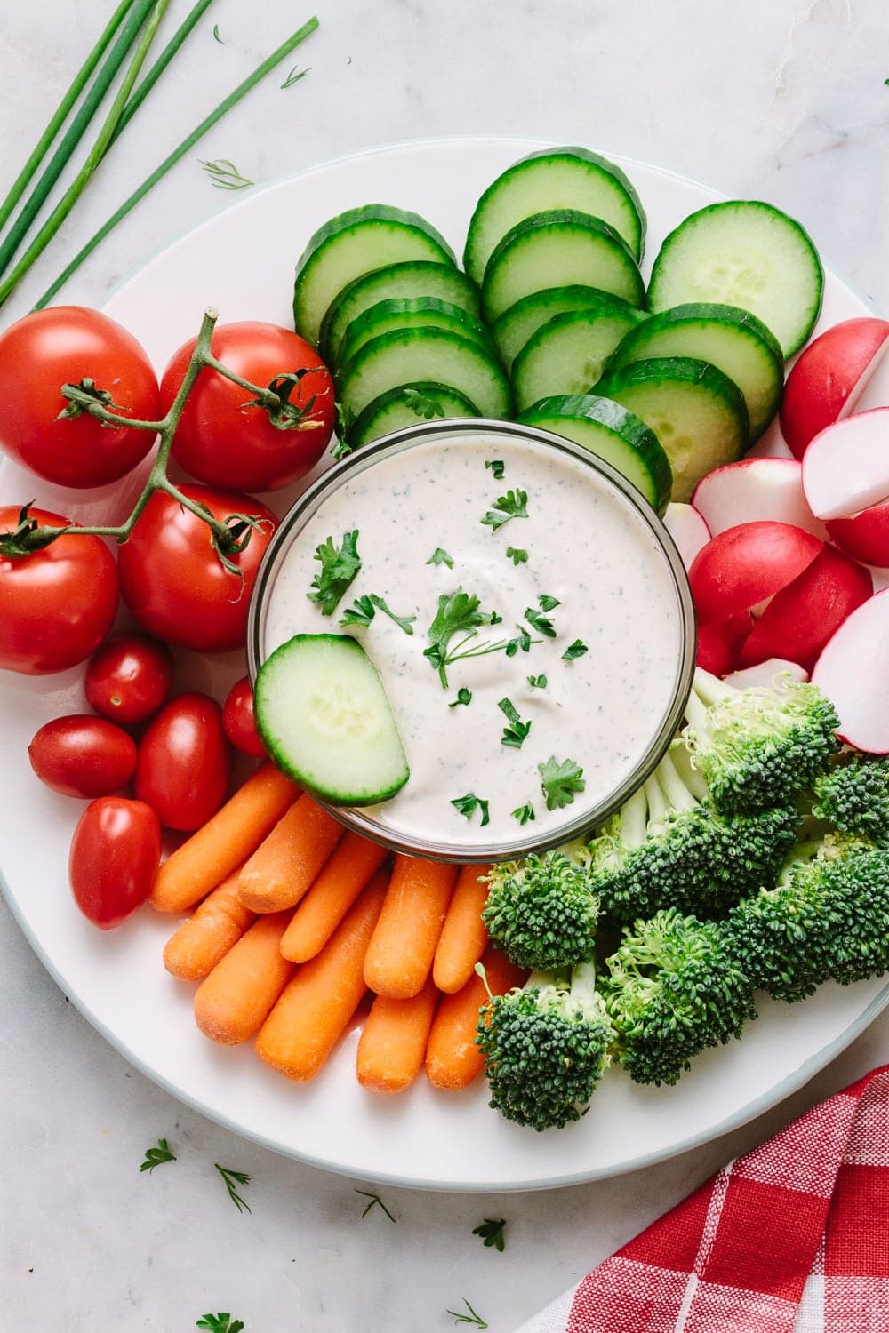 top down view of a platter plate with fresh veggies and small bowl of easy vegan ranch dressing-dip in the center with dipped cucumber.