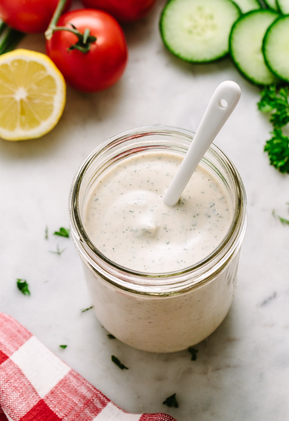 side angle top down view of easy vegan ranch dressing in a glass mason jar with white spoon.